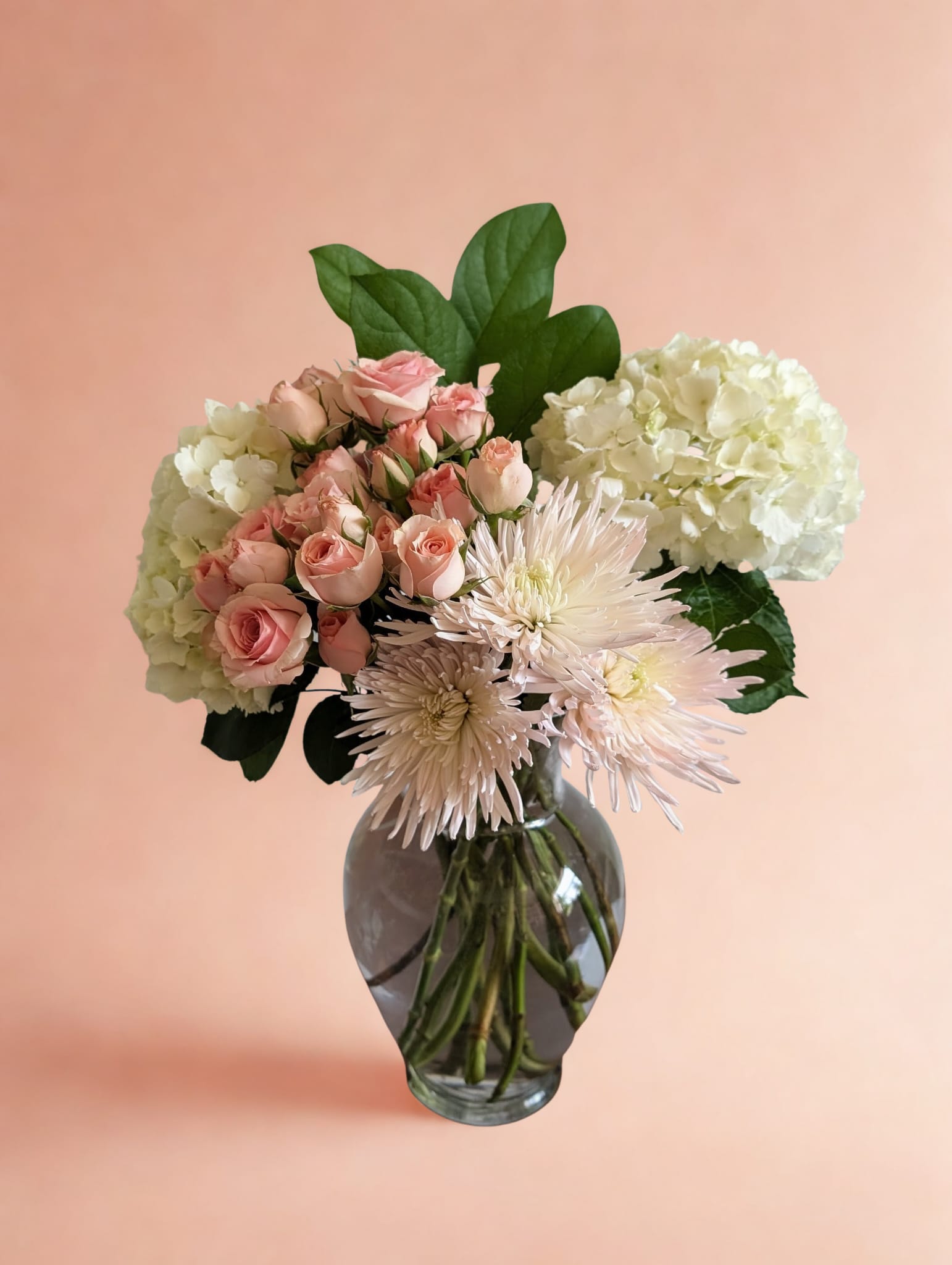 Champagne Garden floral arrangement with blush spray roses, cream hydrangeas, and pale spider mums in a clear glass vase