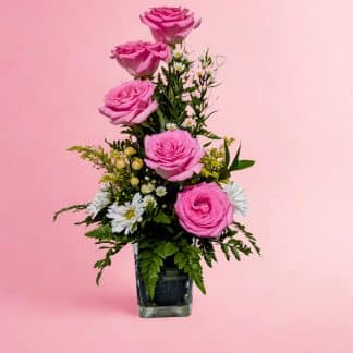 Cascading pink rose vase arrangement with white daisies and golden hypericum berries in a black cube vase — Irus Floral Design